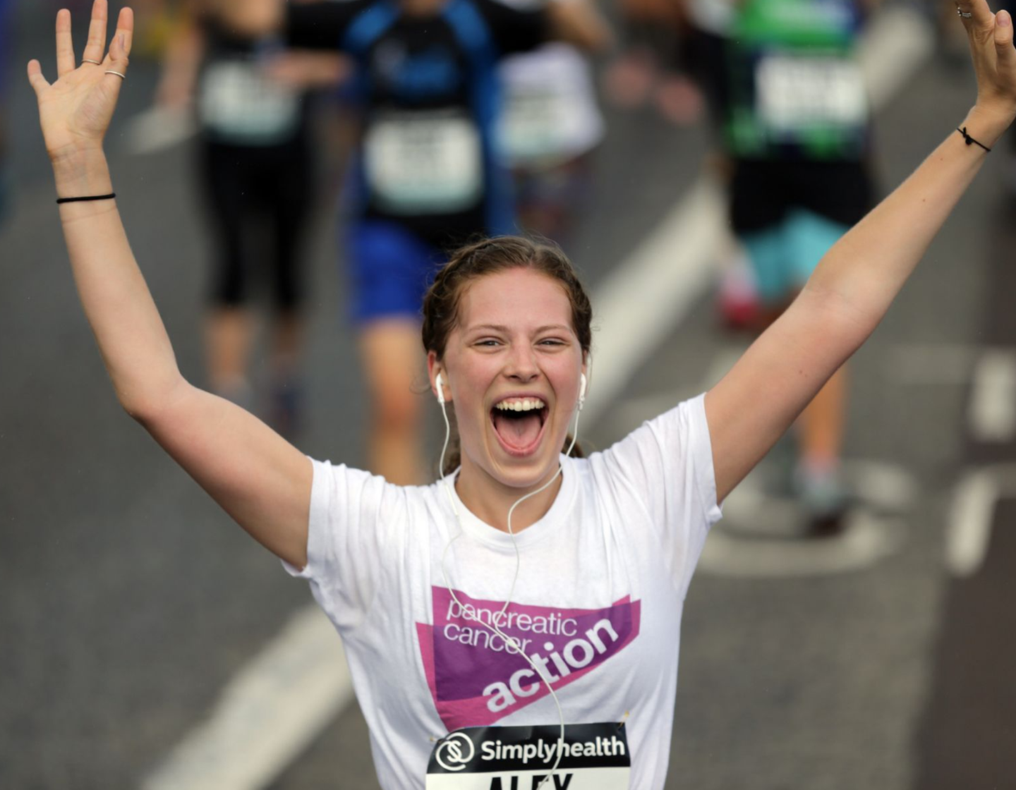 Woman wearing a PCA branded t-shirt celebrates completing a running event