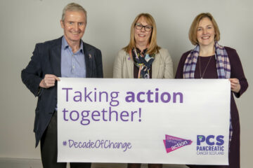 Ross Carter, Ali Stunt and Fiona Brown holding a banner that reads "Taking Action Together"