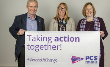 Ross Carter, Ali Stunt and Fiona Brown holding a banner that reads "Taking Action Together"